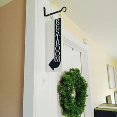 a door with a wreath and an arrow hanging on the wall next to a sign that says rest room