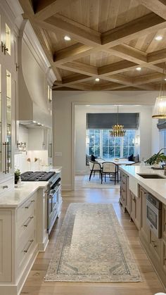 a large kitchen with wooden ceiling and white cabinets, along with an area rug on the floor