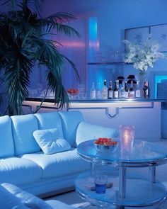 a living room with white couches and blue lighting on the walls, in front of a bar