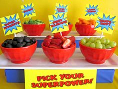 a table topped with red bowls filled with fruits and veggies next to a sign that says kick your super power