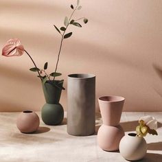 three vases with flowers in them sitting on a table next to each other,