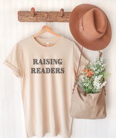 Raising Readers Tee / Homeschool Mom T-shirt / Homeschool - Etsy Relaxed Fit Bookish Tops With Text Print, Bookish Short Sleeve T-shirt For Spring, Spring Bookish Short Sleeve T-shirt, Spring Bookish Style Short Sleeve T-shirt, Spring Bookish T-shirt With Letter Print, Spring Cotton T-shirt With Bookish Style, Bookish Short Sleeve Tops For Spring, Cotton Slogan T-shirt, Spring Bookish Short Sleeve Tops