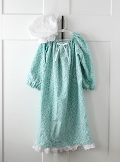 a baby's dress hanging on a door with a tissue dispenser