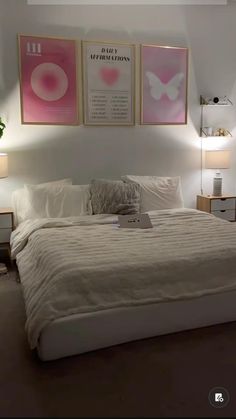 a white bed sitting in a bedroom next to two pictures on the wall above it