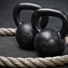 two black kettles sitting on top of a rope