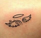 an angel tattoo on the back of a woman's left shoulder, with two wings