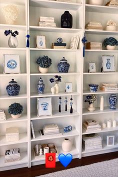 a white bookcase filled with lots of blue and white vases on top of shelves