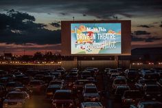 the drive in movie theater is full of cars at night with an advertisement on the screen