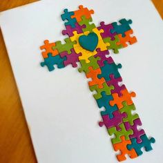 a cross made out of puzzles on top of a piece of paper with a heart in the center