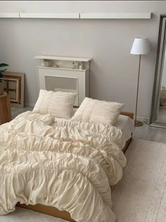 a bed with white sheets and pillows in a room next to a lamp on a table