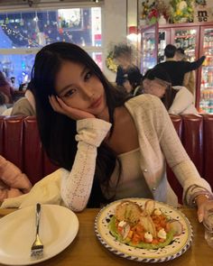 a woman sitting at a table with a plate of food in front of her,