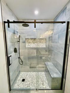 a walk in shower sitting next to a white tiled wall and floor with glass doors