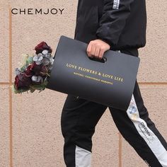 a man walking down the street carrying a bag with flowers on it and a bouquet