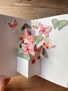 someone is holding an open book with some butterflies on the pages and paper cut out to look like flowers