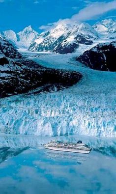 a boat floating on top of a body of water next to snow covered mountains