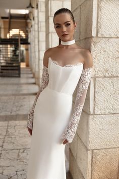 a woman in a white wedding dress leaning against a wall