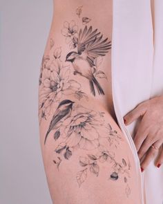 a woman's thigh with flowers and birds on it