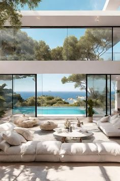 a living room filled with lots of white furniture and large windows overlooking the water's edge