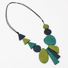 "Green Long Alexis Necklace A fun necklace for the art lover. Geometric wood beads are hand painted in green and blues and stacked together in a unique pattern on an adjustable black wax cord. Wear it long or short, you can't go wrong. Finish your look with coordinating statement earrings or a fun bracelet! Adjustable Length: 24\"-38\" Care Instructions: Remove Sylca Statement jewelry when applying perfumes, creams, washing hands etc. Do not store in direct sunlight. To restore color and shine a Gold Bib Necklace, Jewelry Big, Washing Hands, Wooden Bead Necklaces, Spike Necklace, Necklace Art, Fun Bracelet, Chunky Statement Necklace, Bold Necklace