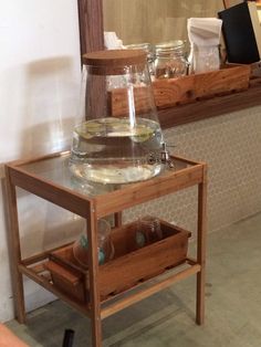 a wooden table topped with a glass vase filled with water and other items next to a mirror