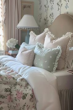 a bed with many pillows on it and a lamp next to the headboard in front of them