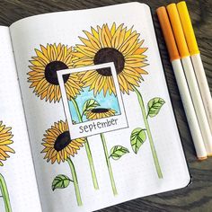 an open notebook with sunflowers on it next to some markers and pencils