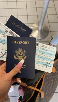 a person holding a passport in their hand and boarding tickets on the other side of them