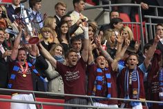 a group of people standing next to each other in front of a crowd holding up trophies