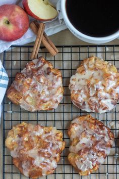 apples and cinnamon rolls on a cooling rack next to an apple, cinnamon sticks, and cup of coffee