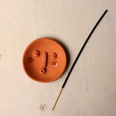 an orange plate with two faces on it next to a paintbrush and some water drops