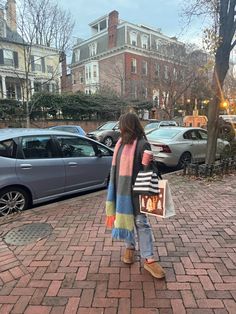 a woman is standing on the sidewalk with her shopping bag in hand and cars parked behind her