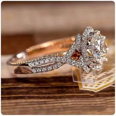 a diamond engagement ring with an orange and white center surrounded by diamonds on top of a wooden table