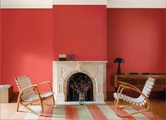 two rocking chairs in front of a fireplace with red paint on the walls and floor