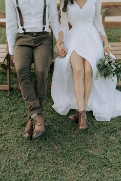 a bride and groom sitting on a bench holding hands with each other in the grass