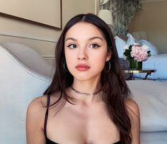 a woman in a black dress sitting on a couch with her eyes closed and wearing large hoop earrings