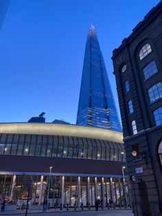 a very tall building sitting next to other buildings in the city at night with lights on