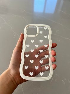 a hand holding a phone case with white hearts on the front and back cover in clear