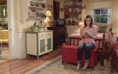 a woman sitting on a red bench in a living room looking at her cell phone