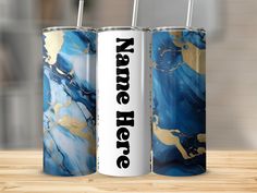 two blue and gold water bottles with straws in them sitting on a wooden table