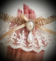 This vintage look garter is lovely in light ivory net lace over a champagne satin band. Decorated with a faux pearl and crystal finding. This garter is also available in plus size, just convo me with questions or your own design ideas! A blue satin rolled rose can be added to the inside of the band for your 'something blue'. Packaged in a view-top box tied with an elastic metallic bow, perfect for gift-giving or for safe-keeping after the wedding. Elegant Lace Bridal Accessories For Bridal Shower, Formal Cream Fitted Bridal Accessories, Elegant Cream Lace For Bride, Adjustable Lace Bridal Accessories For Ceremony, Elegant Bridal Accessories With Lace Trim For Wedding, Fitted Cream Bridal Accessories For Ceremony, Elegant Wedding Bridal Accessories With Lace Trim, Elegant Fitted Lace Bridal Accessories, Vintage Cream Lace For Ceremony