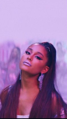 a woman with long hair standing in front of a pink wall and looking up at the sky