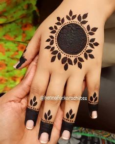 a woman's hand with black henna tattoos on her left hand and fingers