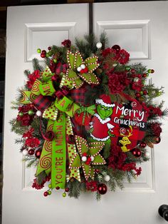 a christmas wreath on the front door of a house that has been decorated with red, green and white decorations