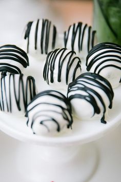 chocolate covered desserts are arranged on a white platter with flowers in the background