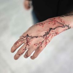 a person's hand with red flowers painted on it and the palm of their left hand