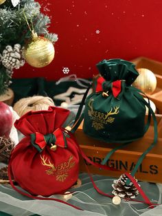 two christmas bags sitting on top of a table next to pine cones and other decorations