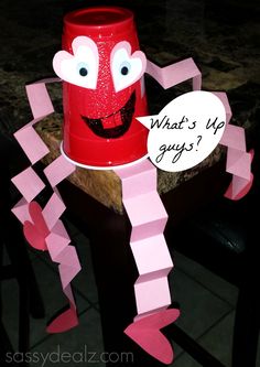 a red cup sitting on top of a table next to a paper cut out character