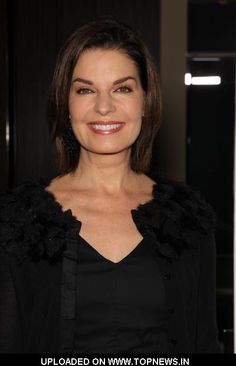 a woman wearing a black dress and fur collar smiling at the camera with her hands in her pockets