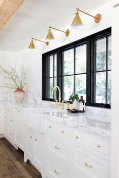 a kitchen with marble counter tops and brass fixtures, along with two windows that look out onto the outdoors