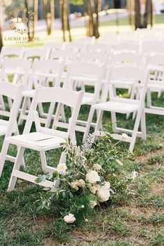 white folding chairs are set up in the grass for an outdoor ceremony with flowers and greenery